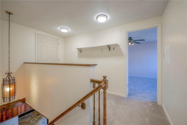 hall with light carpet and a textured ceiling