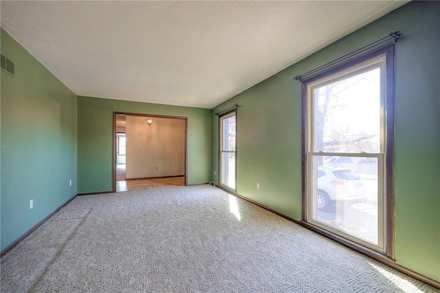 carpeted empty room with a textured ceiling