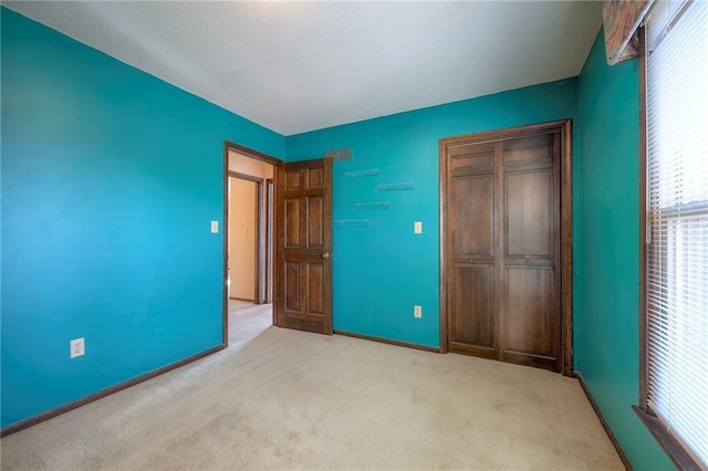 unfurnished bedroom with light carpet and a closet