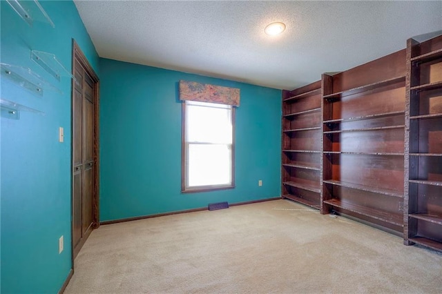 unfurnished bedroom featuring light carpet and a textured ceiling