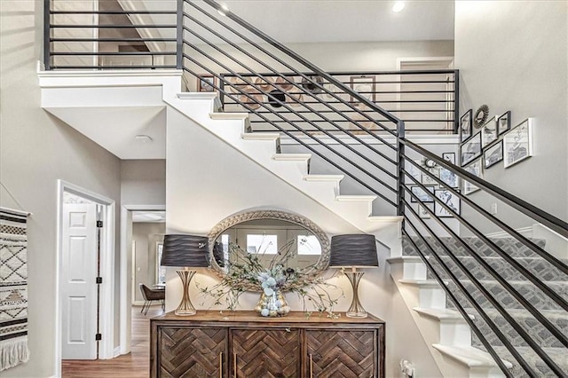 stairway featuring wood-type flooring and a towering ceiling