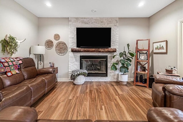 living room featuring a stone fireplace and light hardwood / wood-style flooring