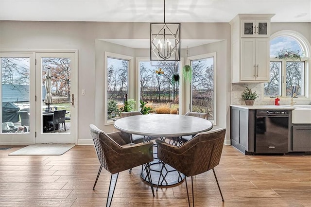 dining room featuring sink, a chandelier, light hardwood / wood-style floors, and a wealth of natural light