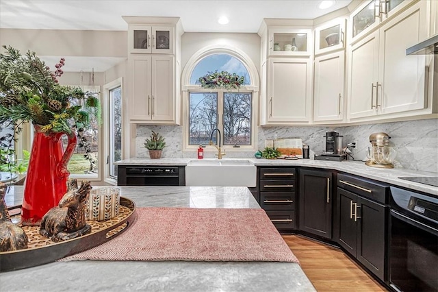 kitchen with tasteful backsplash, sink, white cabinets, light hardwood / wood-style floors, and black appliances