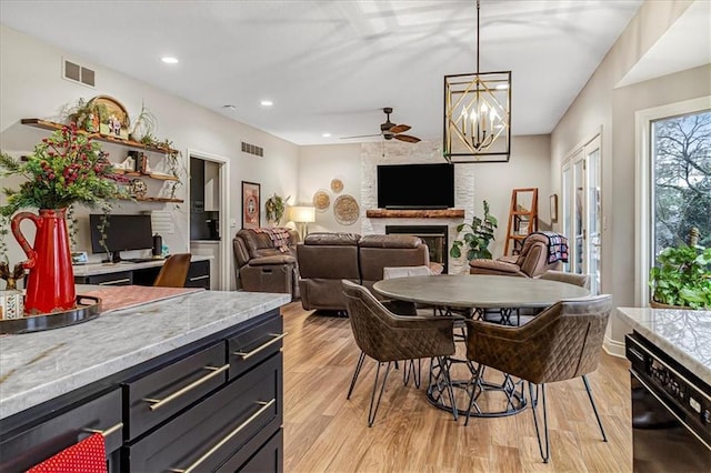 dining space with ceiling fan, a fireplace, and light hardwood / wood-style floors