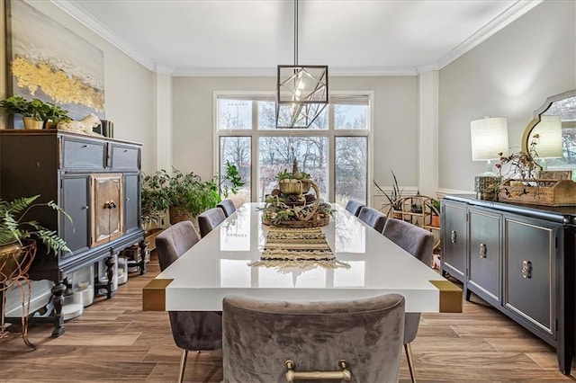 dining area with crown molding, an inviting chandelier, and light hardwood / wood-style flooring