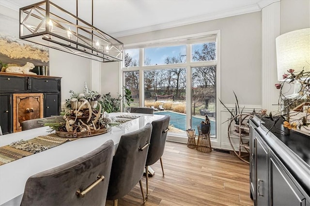 dining area featuring a notable chandelier, ornamental molding, and light wood-type flooring