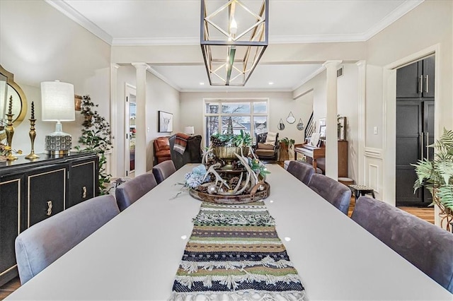 dining area featuring crown molding, an inviting chandelier, and decorative columns