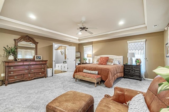 carpeted bedroom with ceiling fan, ensuite bathroom, and a tray ceiling