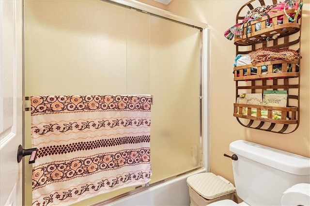 bathroom featuring enclosed tub / shower combo and toilet