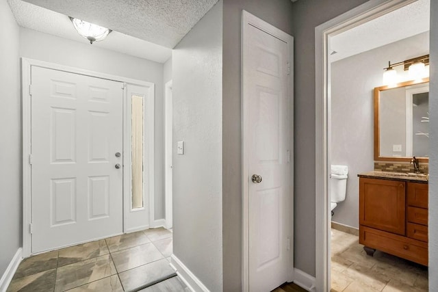 tiled foyer entrance with sink and a textured ceiling