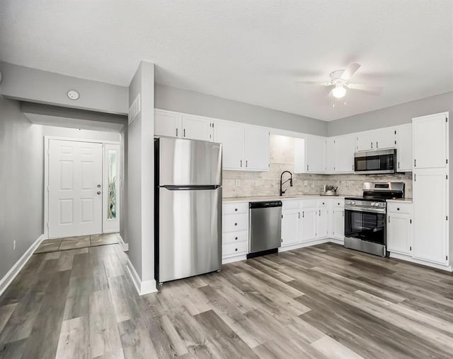 kitchen with white cabinetry, sink, light wood-type flooring, and appliances with stainless steel finishes