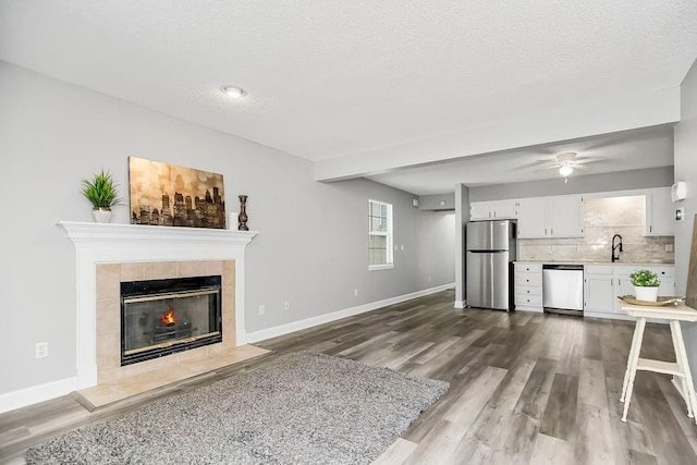 unfurnished living room featuring sink, a textured ceiling, a fireplace, and wood-type flooring