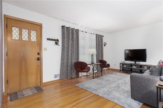 living area with visible vents, baseboards, and wood finished floors