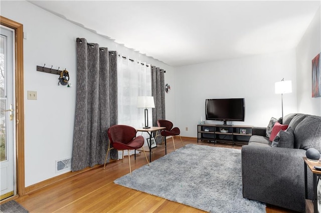 living room with wood finished floors, visible vents, and baseboards