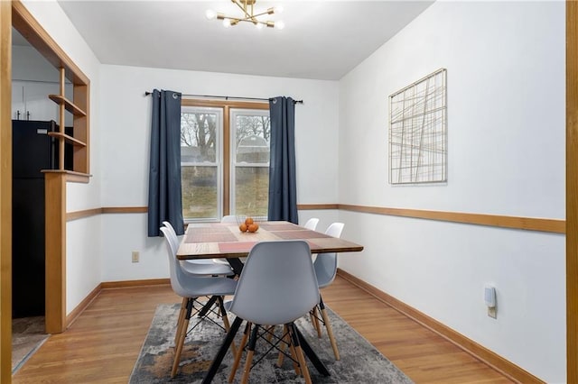 dining room featuring an inviting chandelier, light wood-style flooring, and baseboards