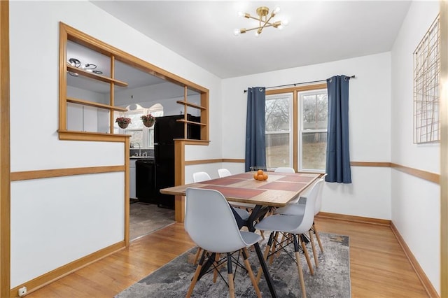 dining room featuring light wood-type flooring, an inviting chandelier, and baseboards