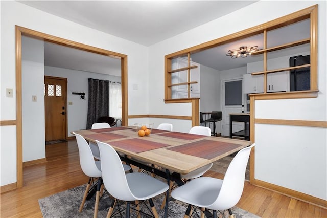 dining room featuring light wood finished floors and baseboards