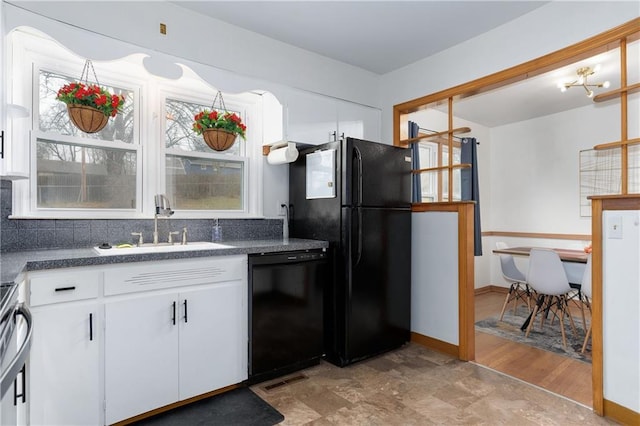 kitchen with white cabinets, dark countertops, a sink, black appliances, and backsplash