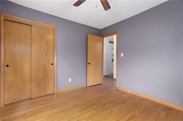 unfurnished bedroom with light wood-style flooring, baseboards, ceiling fan, and a closet