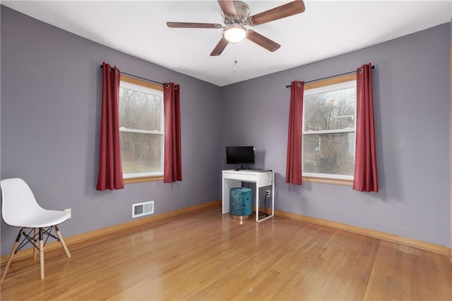 unfurnished office featuring light wood finished floors, baseboards, visible vents, and ceiling fan