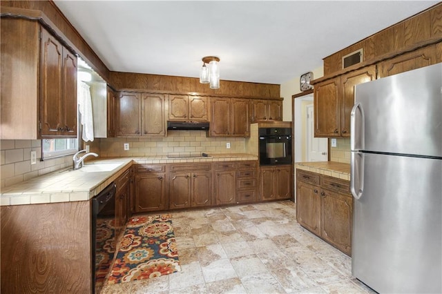 kitchen featuring backsplash, tile countertops, sink, and black appliances