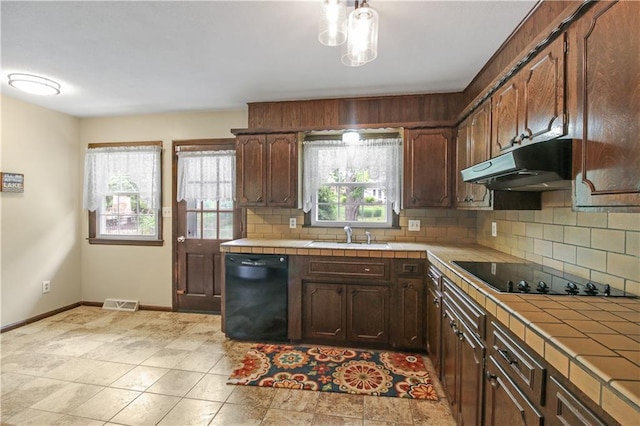 kitchen featuring sink, decorative backsplash, tile counters, black appliances, and dark brown cabinets