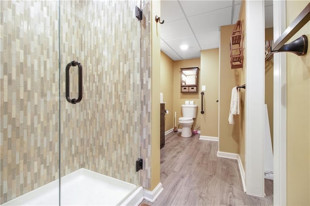 bathroom featuring a paneled ceiling, toilet, an enclosed shower, and hardwood / wood-style floors