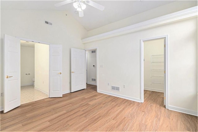 unfurnished bedroom featuring a walk in closet, ensuite bathroom, and light wood-type flooring