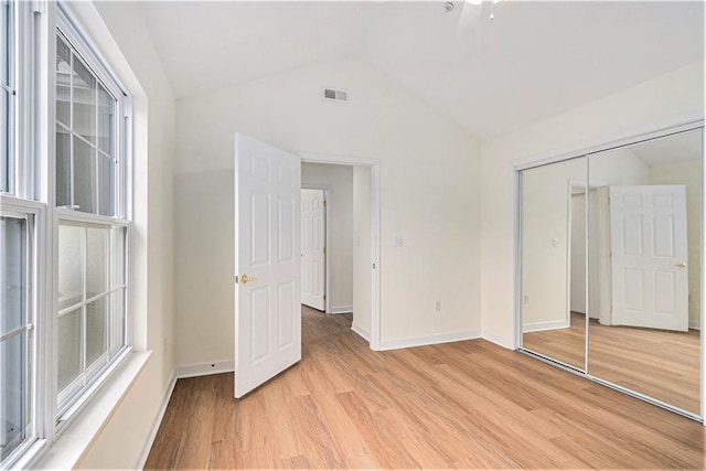 unfurnished bedroom with lofted ceiling, light wood-type flooring, and a closet