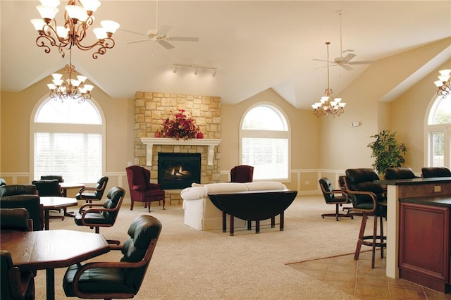 carpeted living room with high vaulted ceiling, a fireplace, and ceiling fan with notable chandelier