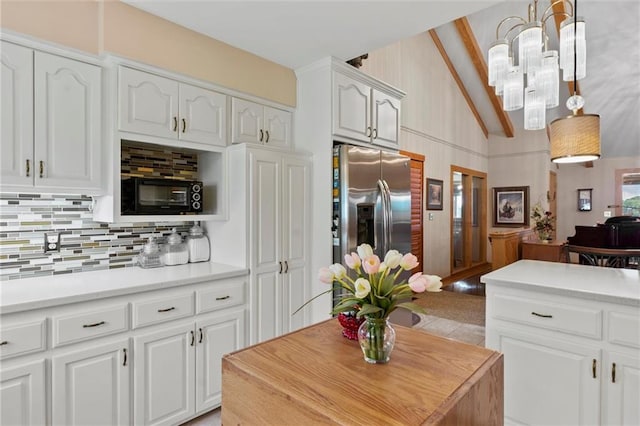 kitchen with white cabinetry, stainless steel fridge, hanging light fixtures, and backsplash