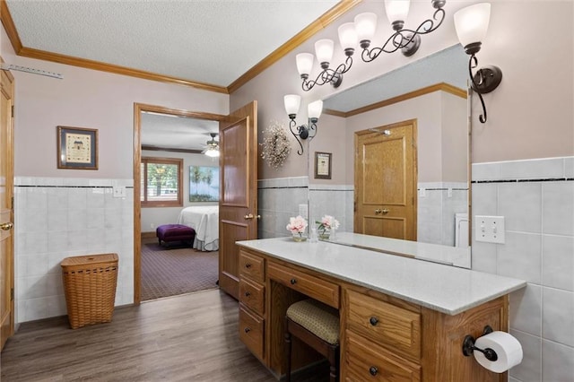 bathroom with tile walls, a textured ceiling, ornamental molding, vanity, and hardwood / wood-style flooring