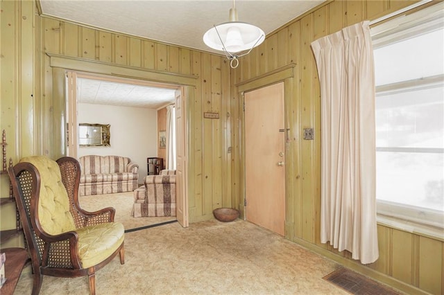 sitting room featuring carpet, wooden walls, and visible vents