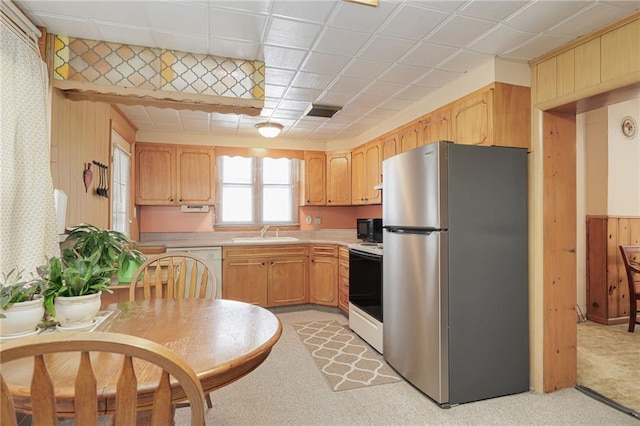 kitchen featuring light carpet, white appliances, wood walls, a sink, and light countertops