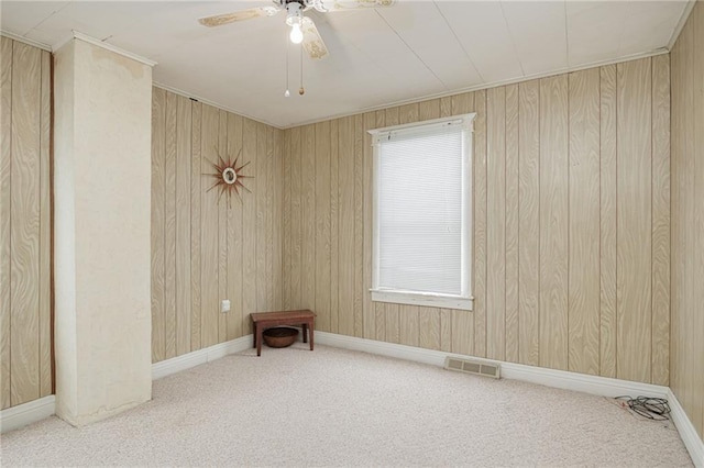 spare room featuring baseboards, visible vents, a ceiling fan, crown molding, and carpet floors