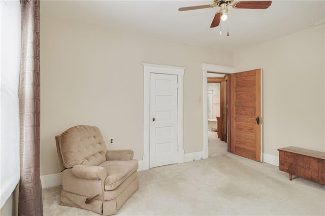 living area with baseboards, ceiling fan, and light colored carpet