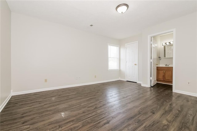 unfurnished bedroom with sink, ensuite bath, and dark wood-type flooring