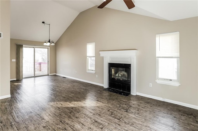 unfurnished living room featuring dark wood-type flooring, high vaulted ceiling, and ceiling fan with notable chandelier