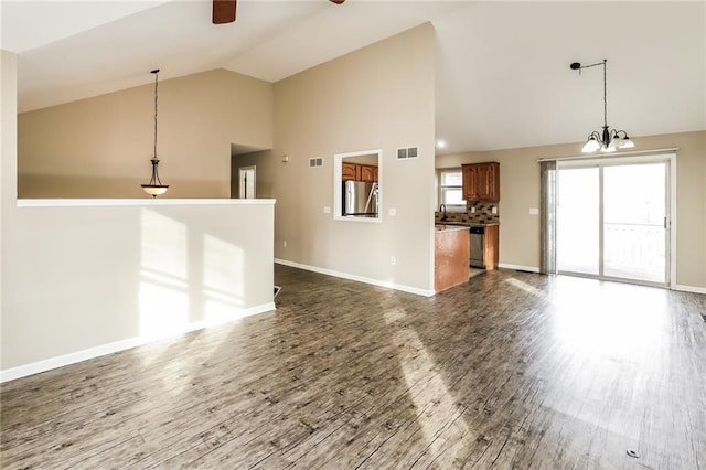 unfurnished living room with high vaulted ceiling, ceiling fan with notable chandelier, and dark hardwood / wood-style flooring