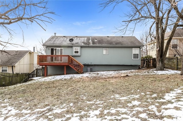 snow covered back of property with a wooden deck