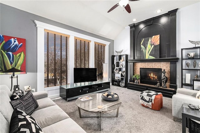 living room with ceiling fan, a fireplace, vaulted ceiling, and carpet