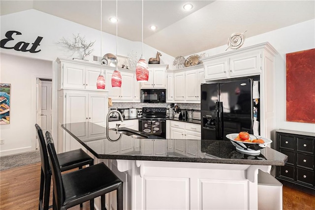 kitchen with sink, black appliances, a large island with sink, a kitchen breakfast bar, and white cabinets