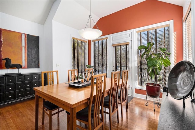 dining area with dark wood-type flooring and vaulted ceiling