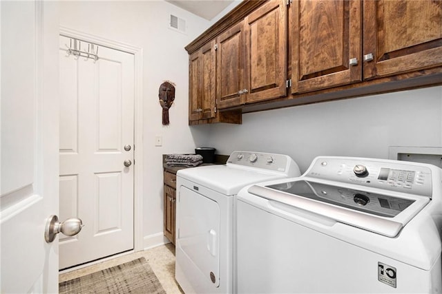 clothes washing area featuring cabinets and separate washer and dryer