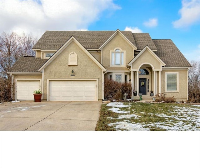 traditional-style home with roof with shingles, driveway, an attached garage, and stucco siding