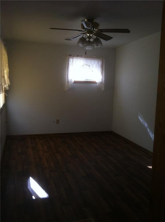 empty room featuring a ceiling fan and dark wood-style flooring