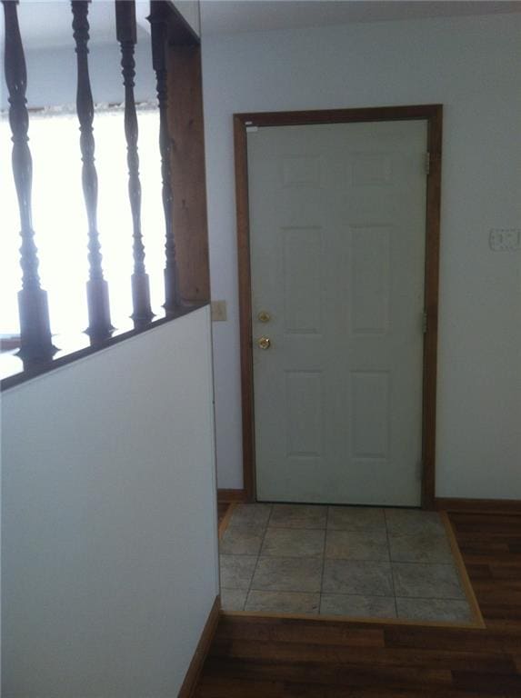 doorway with light tile patterned floors and baseboards