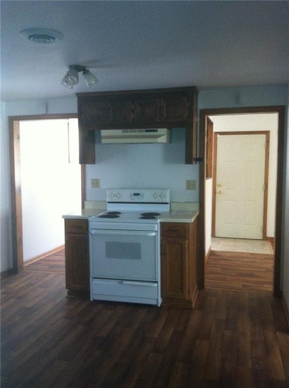 kitchen with under cabinet range hood, dark wood finished floors, light countertops, and white electric range oven