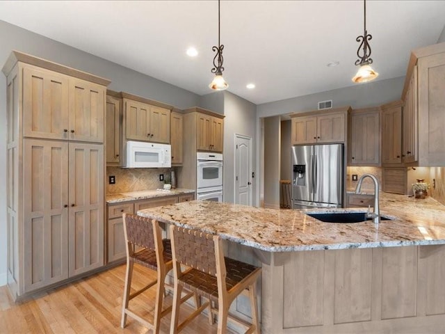 kitchen with visible vents, a sink, tasteful backsplash, white appliances, and a peninsula